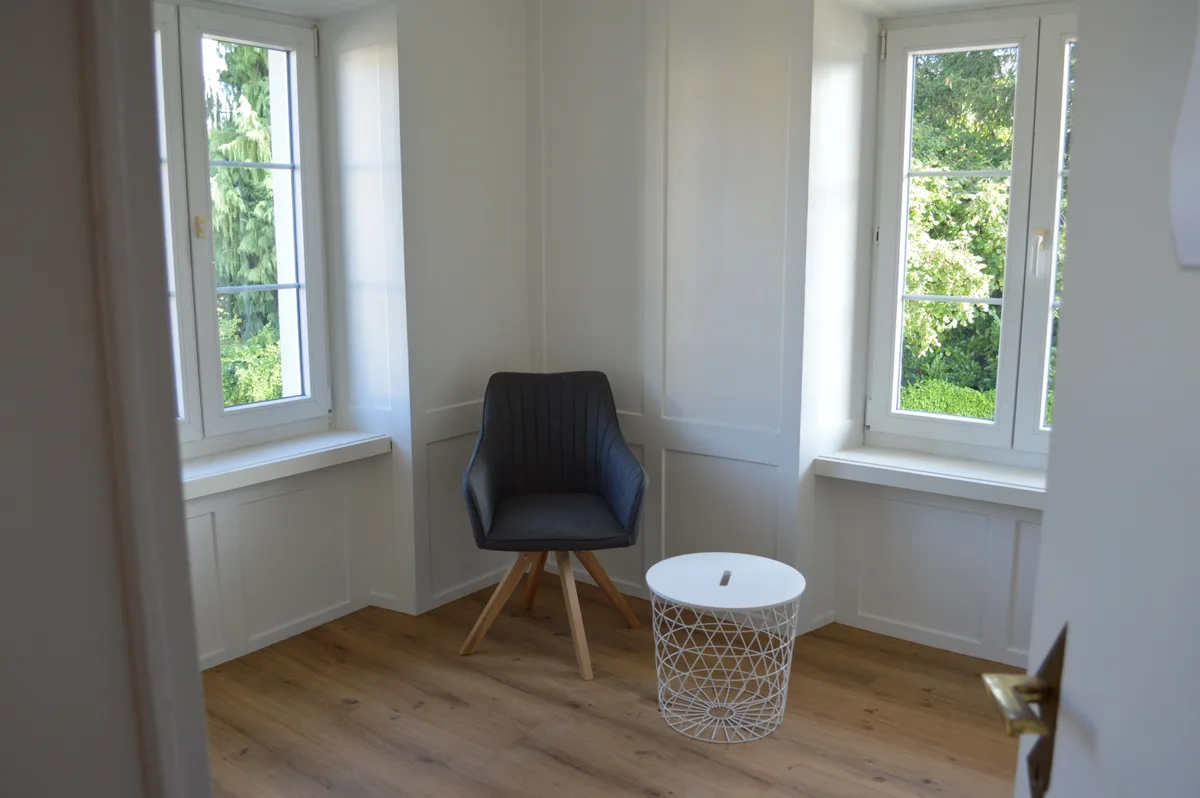 Ein Zimmer mit einem Sessel und einem Tischchen.